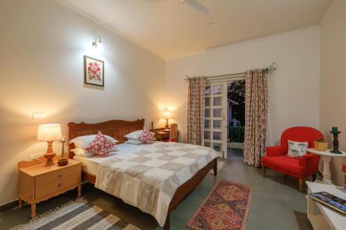 1 dormitorio con 1 cama y 1 silla roja en Shree Nikunj - A Boutique Homestay, en Jaipur