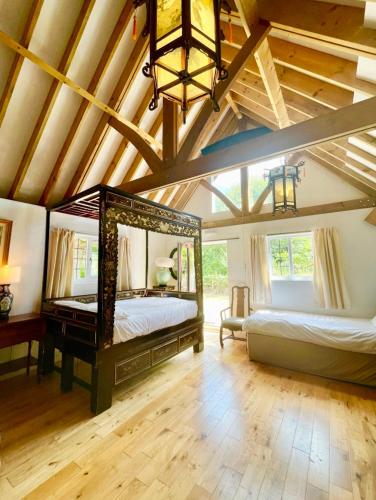 a bedroom with two beds and a ceiling with beams at The Mill House on the Brooks South Downs West Sussex Sleeps 15 in Hardham