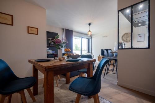 une salle à manger avec une table en bois et des chaises bleues dans l'établissement Appartement 3 pièces à Rennes Chez Guillaume, à Vezin-le-Coquet