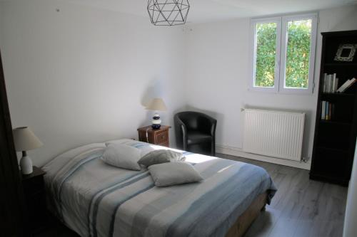 ein Schlafzimmer mit einem Bett mit einem Stuhl und einem Fenster in der Unterkunft Grand T2 au calme, entre mer et montagne in Arbonne
