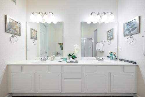 un bagno bianco con due lavandini e due specchi di Vista Cay Poolside Diamond Near Parks & Walk to OCCC a Orlando