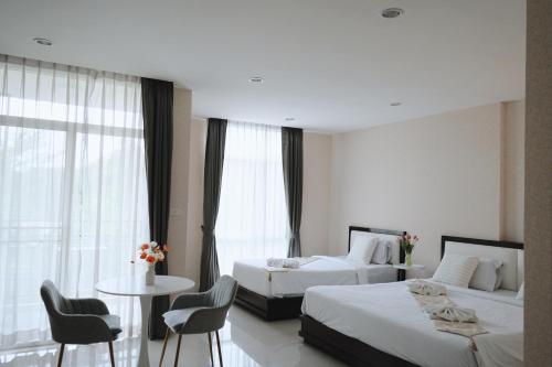 Habitación de hotel con 2 camas, mesa y sillas en Herry Residence, en Chiang Mai