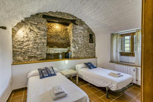 2 Betten in einem Zimmer mit einer Steinmauer in der Unterkunft Mas Cases in Girona