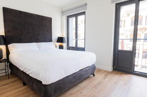 a bedroom with a large bed and two windows at SUITE 1907 OVIEDO COLLECTION in Oviedo