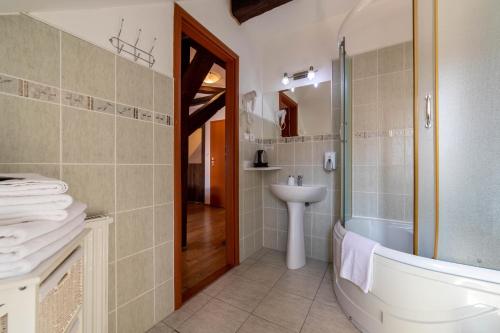 een badkamer met een bad, een wastafel en een douche bij Penzión Zemianska kúria in Dolný Kubín