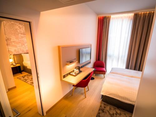 a hotel room with a bed and a desk with a mirror at IntercityHotel Geneva in Geneva
