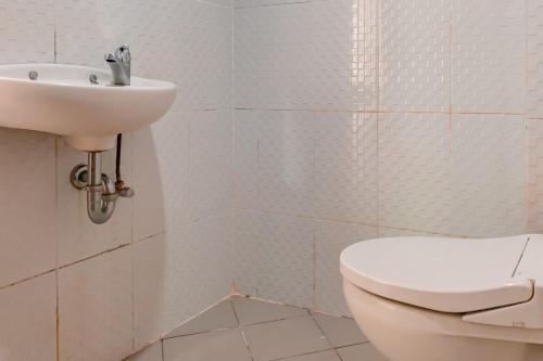 a white bathroom with a toilet and a sink at Urbanview Hotel AVA Banjarmasin by RedDoorz in Banjarmasin