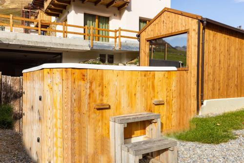 a wooden building with an open door in front of a building at BAITA NOEMI in Livigno