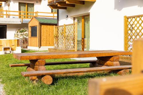 a wooden bench sitting in the grass next to a house at BAITA NOEMI in Livigno