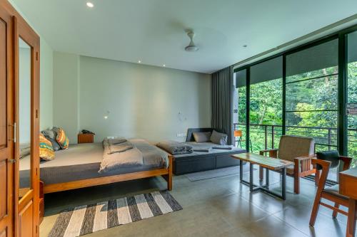 a bedroom with a bed and a table and some windows at K Mansion in Munnar