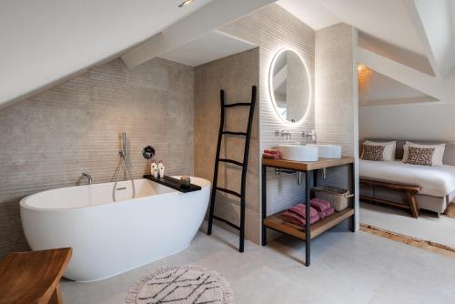 a bathroom with a large white tub and a bedroom at Maison La Belle Cosy 2-bedroom house with jacuzzi & airco in Zoutleeuw