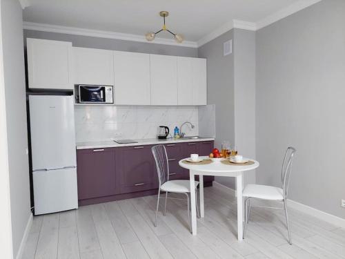 uma cozinha com uma mesa e cadeiras e um frigorífico em ЖК Only sun в 10 минутах от Аэропорта em Prigorodnyy