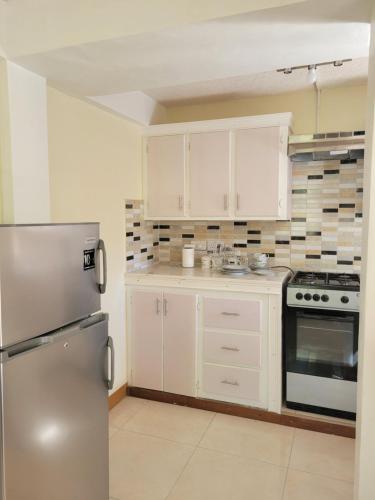 a kitchen with white cabinets and a stainless steel refrigerator at KanXio Apartment in Pointe Michel