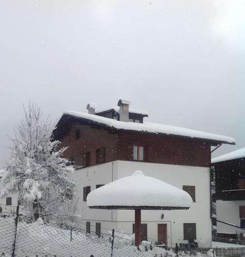 a building covered in snow with an umbrella at Casa Da Rin Elena in Auronzo di Cadore