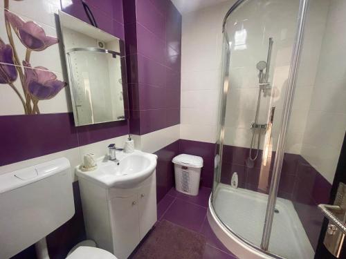 uma casa de banho roxa com um lavatório e um chuveiro. em Discret Apartament One em Târgovişte
