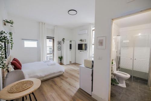 a white bedroom with a bed and a toilet at Bauhaus Studio - Sun Balcony - Rothschild Boulevard in Tel Aviv