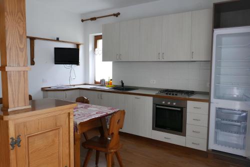 een keuken met witte kasten, een tafel en een fornuis bij Casa Da Rin Giulia in Auronzo di Cadore