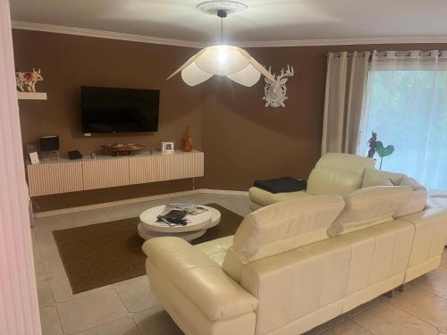 a living room with a white couch and a tv at Chambres d'Hôtes Villa La Louisiane in Arès