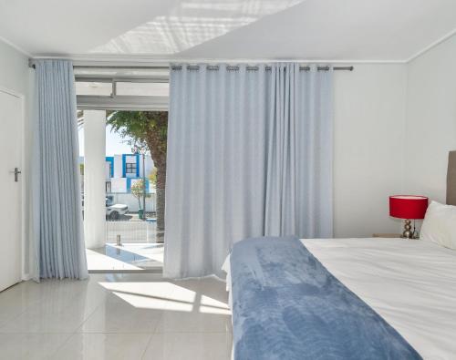 a bedroom with a bed and a large window at Ocean Way Villas - Self Catering in Cape Town