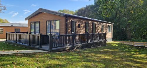 a tiny house with a porch on a lawn at Woolverstone Marina and Lodge Park in Ipswich