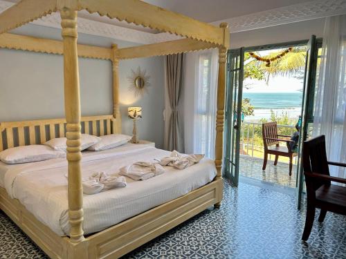 um quarto com uma cama de dossel e vista para o oceano em S2 Beach Cottages em Morjim