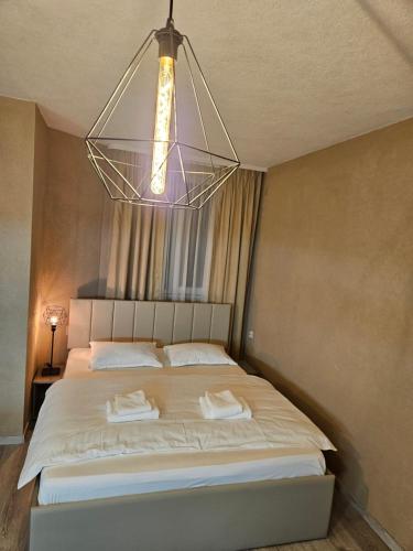 - une chambre avec un grand lit et un lustre dans l'établissement ГеВе Апартаменти, à Sandanski