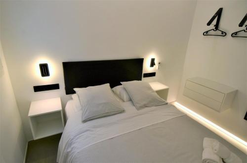 une chambre avec un lit blanc avec deux tables de nuit dans l'établissement BIBLIOTECA DE LUJO EN EL CENTRO HISTORICO DE MÁLAGa, à Malaga