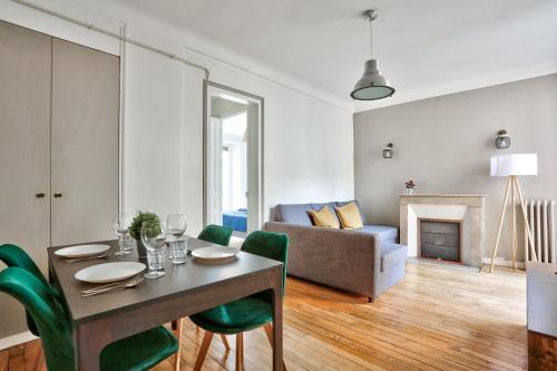 un salon avec une table, des chaises et un canapé dans l'établissement Le Marais Charmant Appartement Paris Free Netflix, à Paris