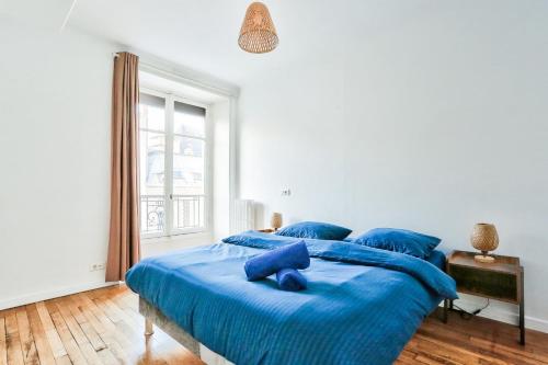 une chambre avec un grand lit bleu avec des oreillers bleus dans l'établissement Le Marais Charmant Appartement Paris Free Netflix, à Paris