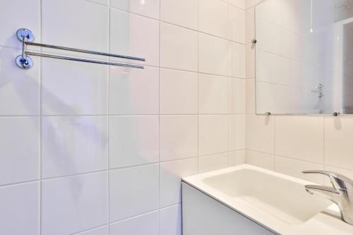 une salle de bain blanche avec un lavabo et un miroir dans l'établissement Le Marais Charmant Appartement Paris Free Netflix, à Paris