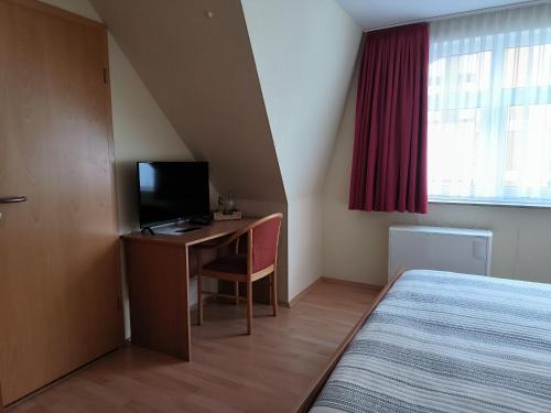 a bedroom with a bed and a desk with a television at Ritters Weinstuben in Merseburg