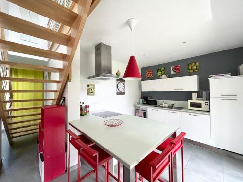 une cuisine avec une table blanche et des chaises rouges dans l'établissement Maison de charme, Les Voiles à Sainte Marine, à Combrit