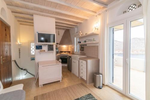 a kitchen with a large window and a tv on the wall at Panormos Art Villas & Suites in Panormos