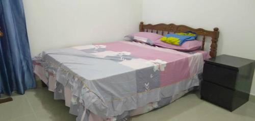 - un lit avec une couverture rose et grise dans l'établissement Faizeen Homestay, à Kuala Kerai