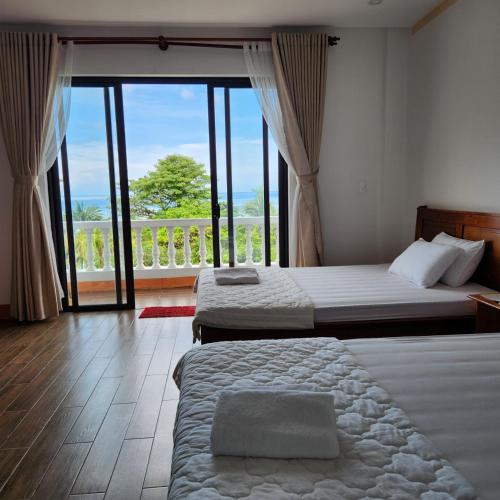 a hotel room with two beds and a large window at Kim Lien Phu Quoc Guesthouse in Phú Quốc