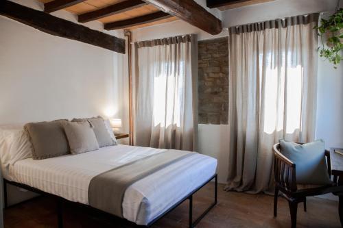 a bedroom with a bed and a chair and windows at Dimidium in Canossa