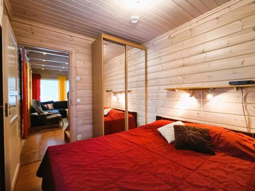 Un dormitorio con una cama roja y un espejo. en Tuohikontti, en Syöte