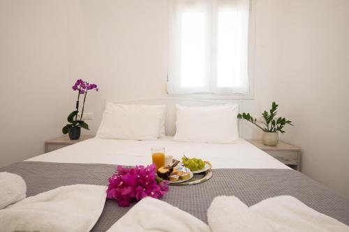 Spilia Apartments & Suites Mykonos في Agrari: سرير عليه صحن من الطعام والزهور