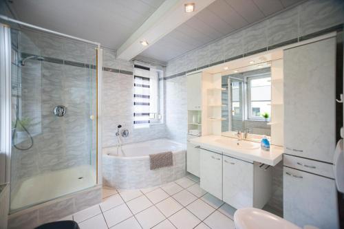 een badkamer met een bad, een wastafel en een douche bij Ferienhaus OG1 "Westerwald Blick" in Martinfeld