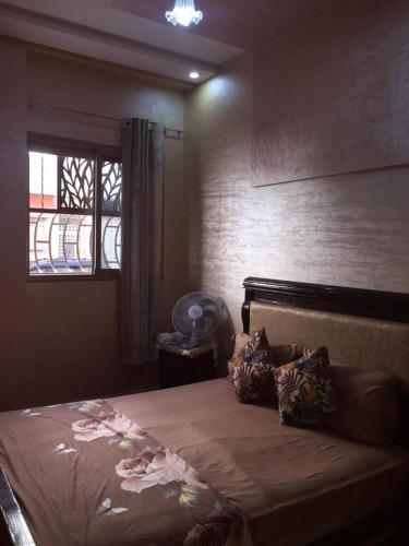 a bedroom with a large bed with a window at Airport M V chambre stay in Deroua