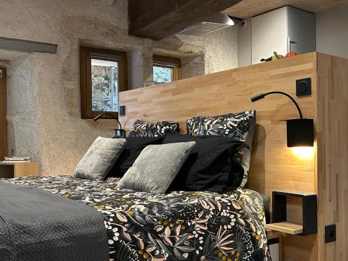 Schlafzimmer mit einem Bett mit schwarzer Bettwäsche und Kissen in der Unterkunft Gite Au pied du Grand Colombier in Talissieu