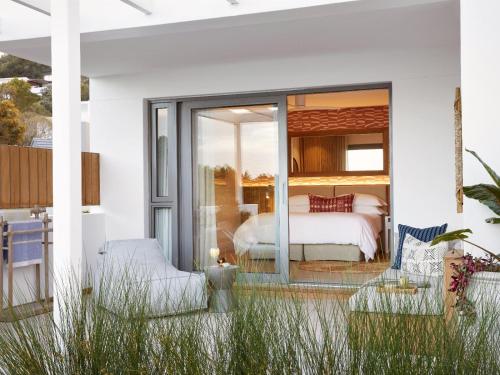a bedroom with a bed and a balcony with grass at Walkers Beach in Plettenberg Bay