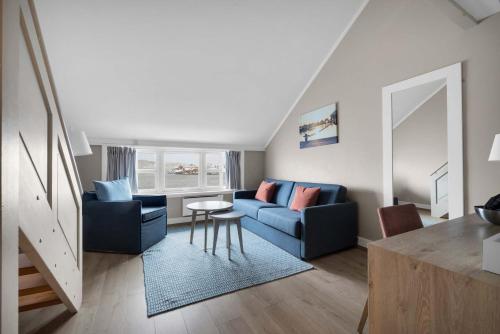 a living room with a blue couch and a table at Clarion Hotel Tyholmen in Arendal