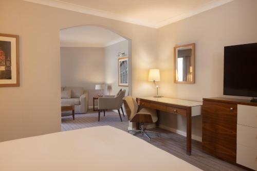 a hotel room with a bed and a desk with a television at Hilton Cambridge City Centre in Cambridge