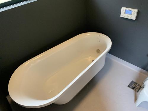 a white bath tub sitting in a bathroom at chigiterasu shintomi miyazaki - Vacation STAY 44990v in Saito