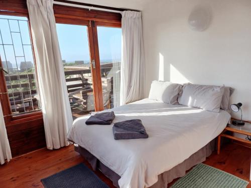 Bett in einem Zimmer mit einem großen Fenster in der Unterkunft The beach cabin with pool in Port Alfred