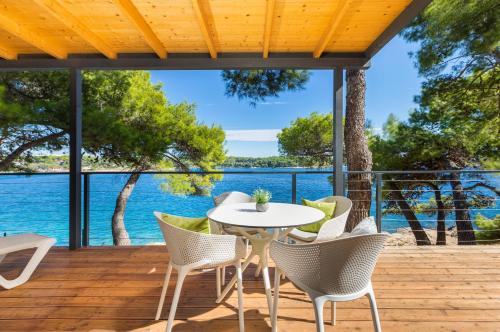 a patio with a table and chairs on a deck with the water at Arena Stoja Camping Homes in Pula