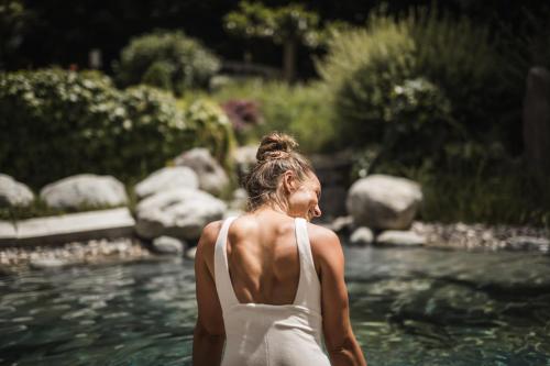 a woman in a white dress standing in a river at Hotel Lanerhof active/spa/balance in San Lorenzo di Sebato