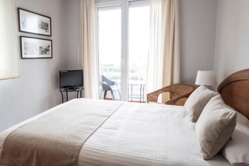 ein Schlafzimmer mit einem großen weißen Bett und einem Fenster in der Unterkunft Piso Avenida de los Castros - Sardinero in Santander