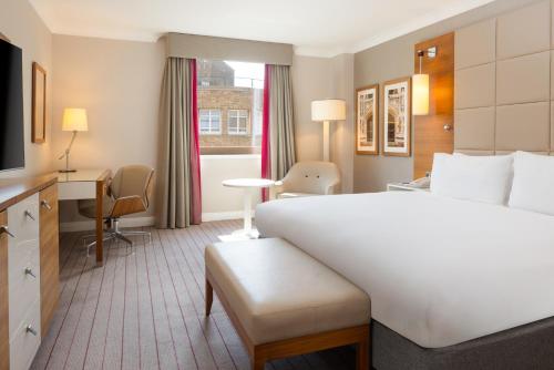 a hotel room with a large white bed and a desk at Hilton Cambridge City Centre in Cambridge